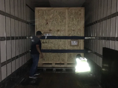 木製梱包箱を固定しているトラック荷台での積載作業