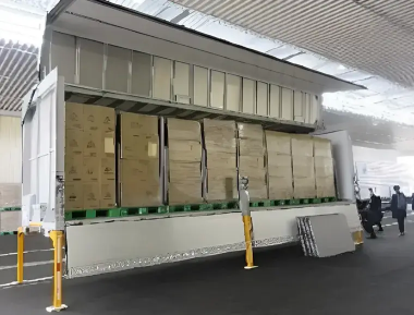 Wing-body truck loaded with palletized cardboard boxes.