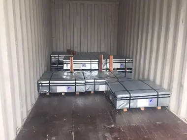 コンテナ内に整然と積み込まれた金属板のパレット。黒い帯で固定され、木製パレットの上に配置されている。安全かつ効率的な貨物輸送の様子を示している。