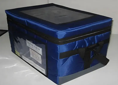 Blue insulated soft cooler box for temperature-controlled transport of pharmaceuticals, with a label window for shipping information.