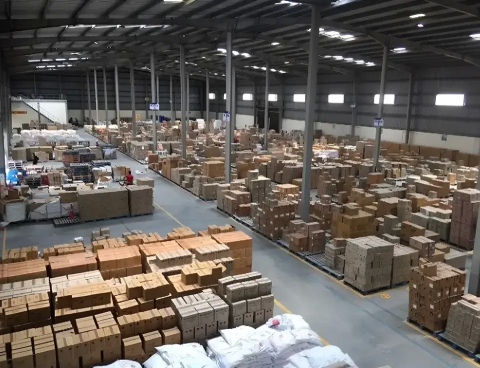 Large warehouse interior with numerous cardboard boxes stacked on pallets.