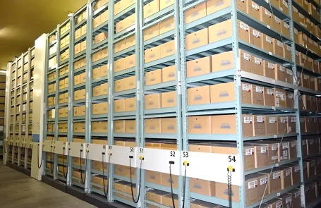 Warehouse shelving with mobile racks neatly lined with cardboard boxes.