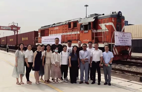 モンゴル鉄道貨物の前で記念撮影をするグループ。赤いディーゼル機関車の前に、関係者が整列して写真を撮っている。